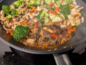 Nahaufnahme: dunkle Balsamico-Reduktion blubbert in der Pfanne neben dem Gemüse.