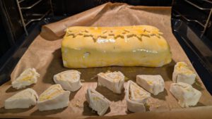 Beef Wellington auf einem mit Backpapier belegten Blech, backfertig, daneben Teigreste