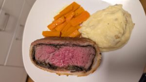 Angerichtete Scheibe Beef Wellington mit Kartoffelpüree und glasierten Karotten