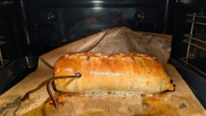 Beef Wellington backt im Ofen, das Kabel eines Bratenthermometers führt hinein