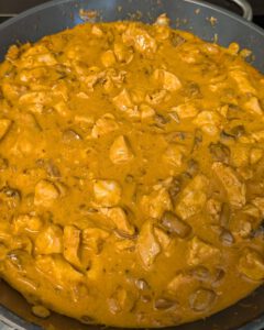 Pfanne mit cremiger, paprikaorangener Chicken-Stroganoff-Soße mit Champignons