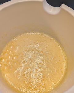 Blassgelbe aufgeschlagene Ei-Zucker-Masse mit feinen Bläschen in einer weißen Rührschüssel