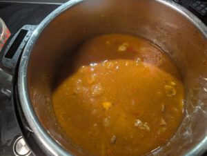 Orangebraune Gulaschsoße mit Champignons und Paprikastücken köchelt in einem Instant Pot aus Edelstahl