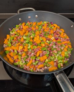 Gewürfelte Pancetta, rote Zwiebel, Karotte und Sellerie garen für das Soffritto in einer breiten Pfanne
