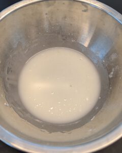 Glatte weiße Glasur aus Puderzucker und Zitronensaft in einer Edelstahlschüssel
